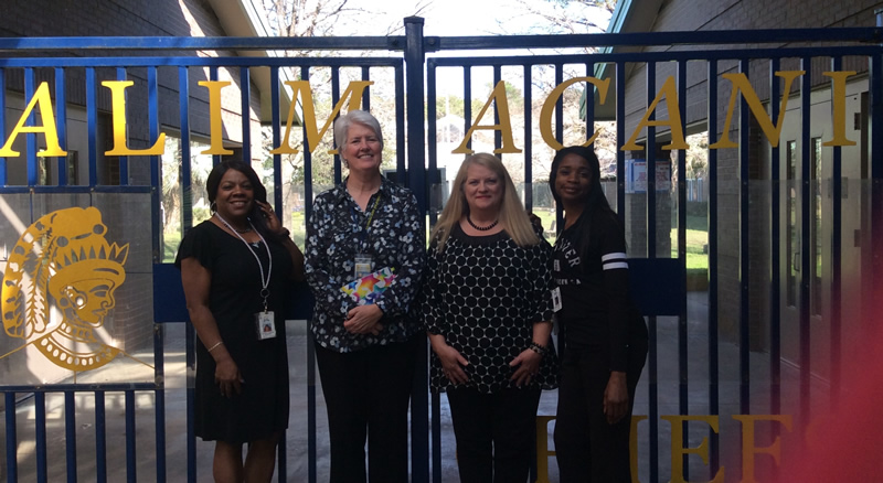 4 women in front of school gates