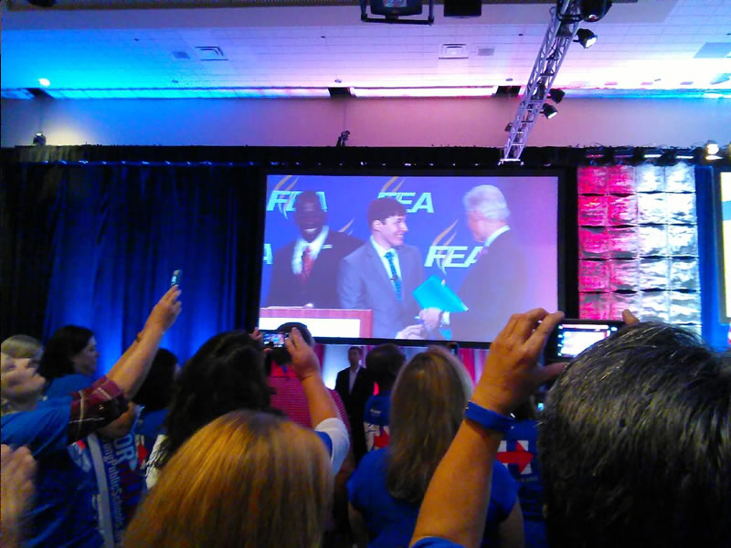 People watching men handshake on stage