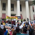Large crowd of people holding signs at rally