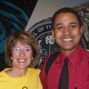 Man in red shirt and black tie next to lady in yellow shirt