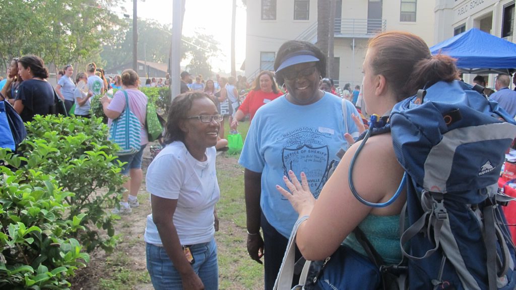 Two ladies talking with lady wearing camping backpack